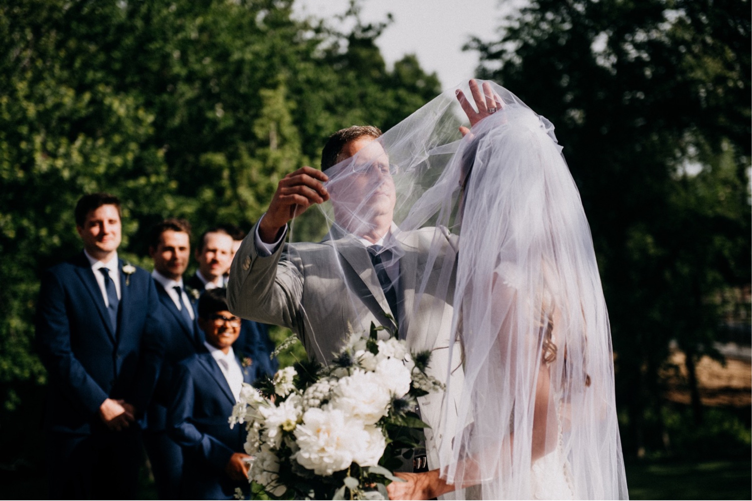 a dad is lifting the veil over his daughter's face during the ceremony portion of a wedding day timeline