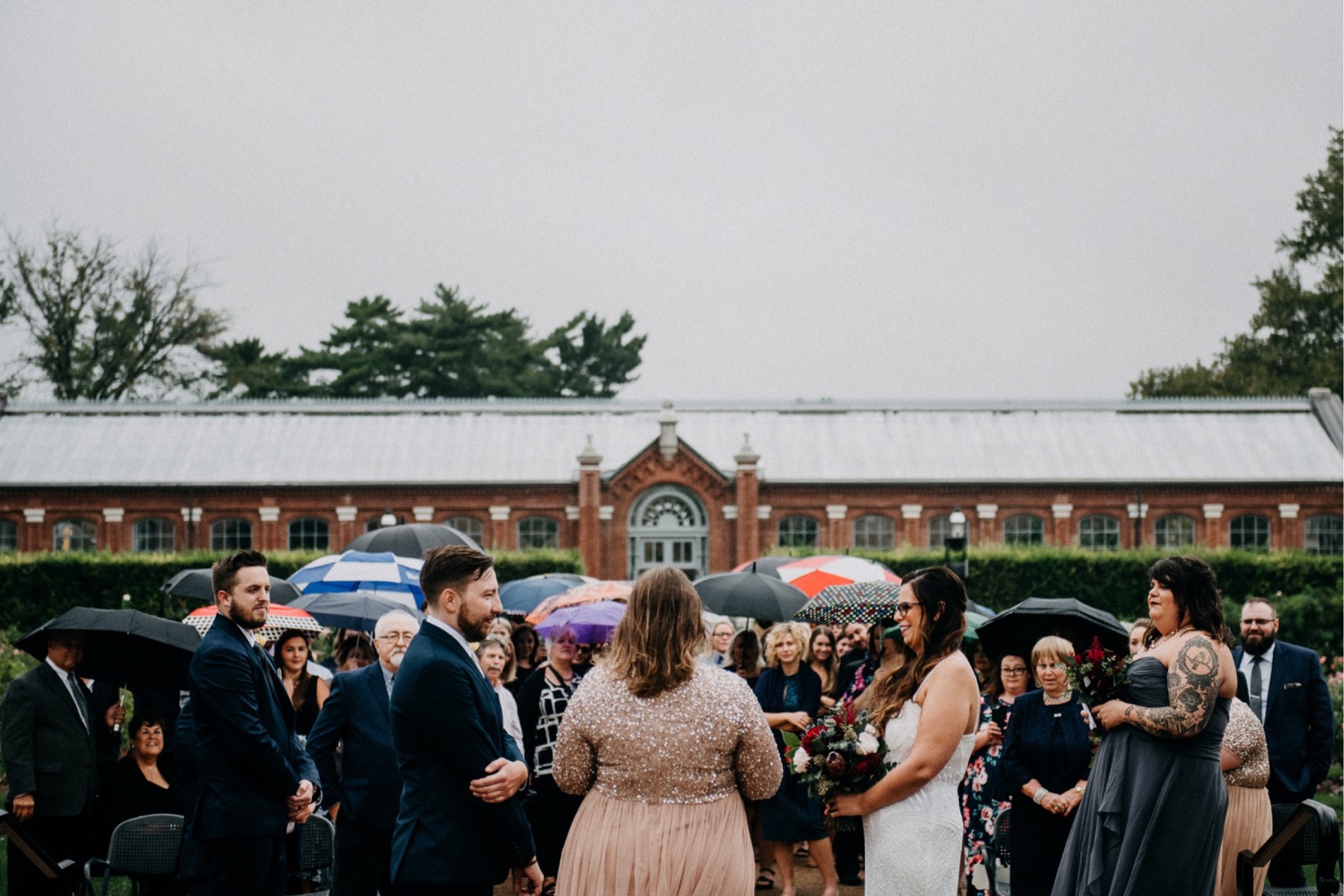 Guests hold umbrellas during a rainy ceremony part of a wedding day timeline