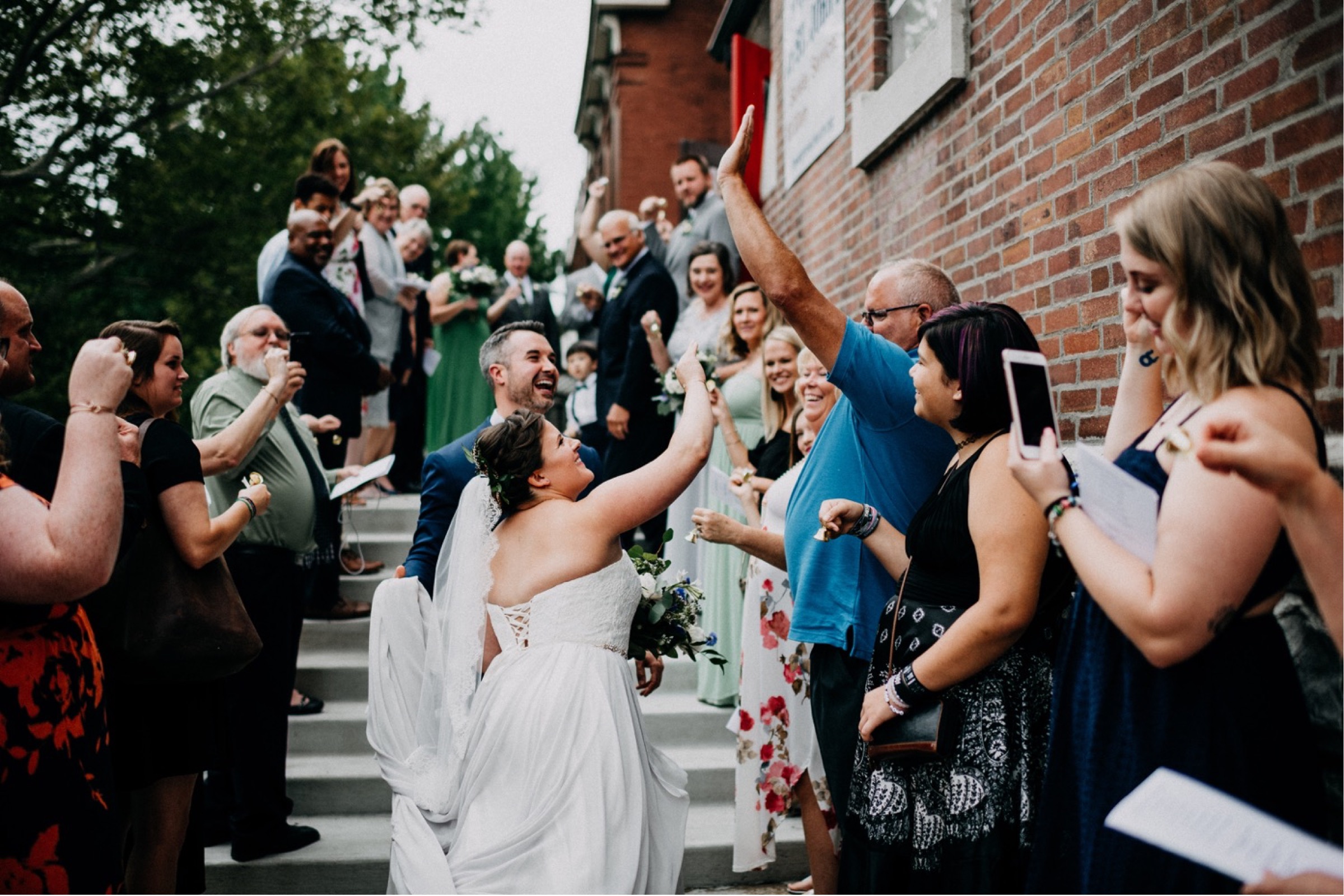 A bride high fives her guests during a receiving line portion of her wedding day timeline.