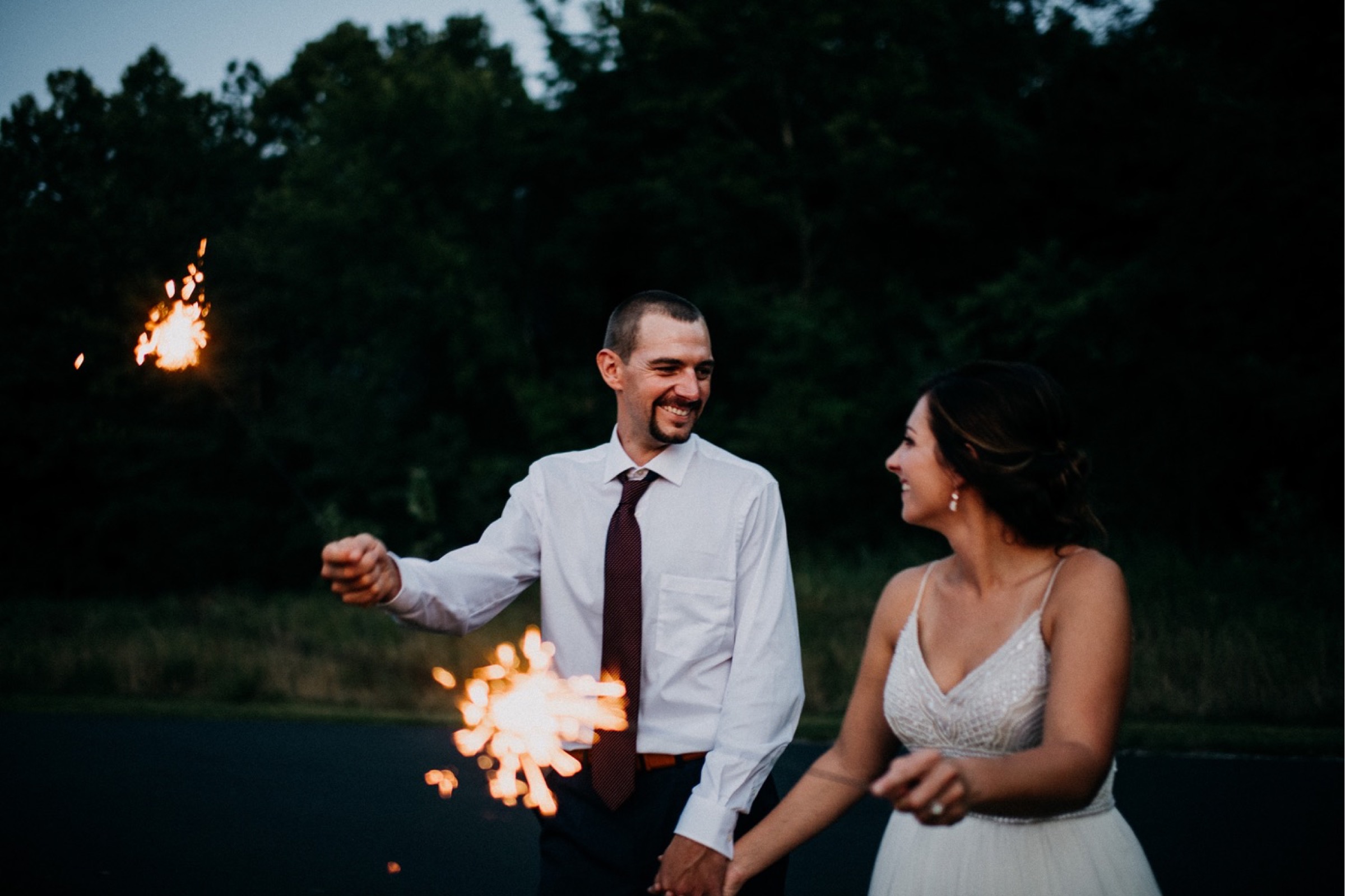 a bride and groom play with sparklers during a sunset portrait portion of the wedding day timeline 