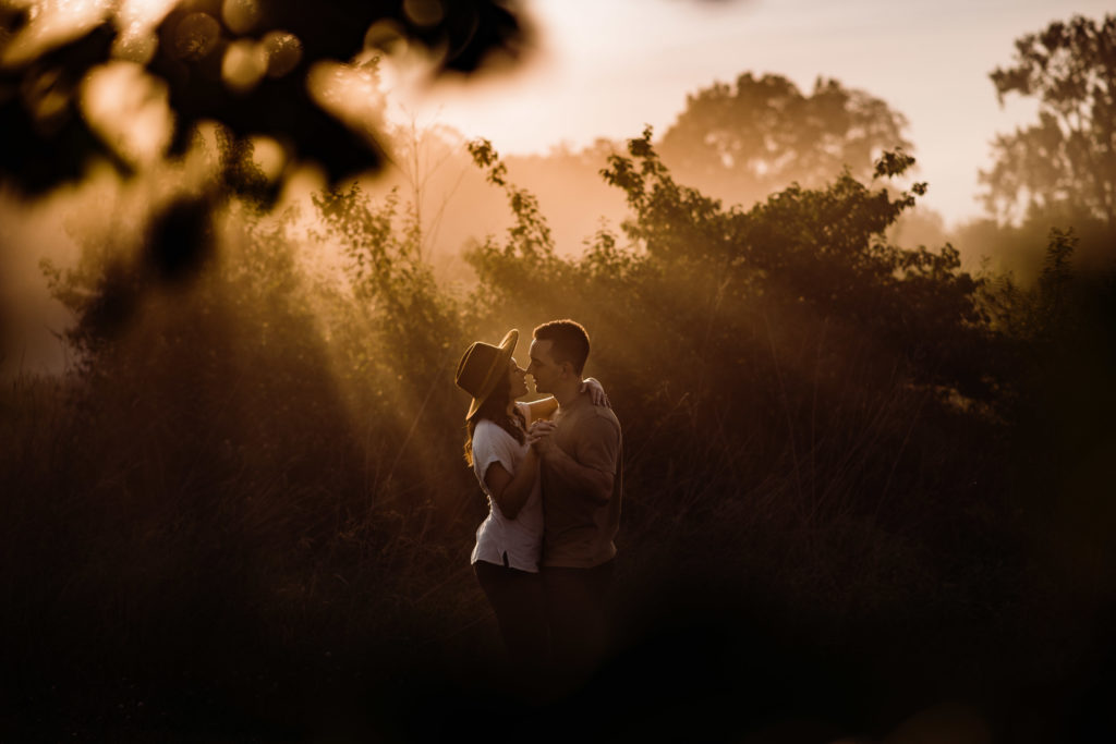man and woman embracing during their engagement session in California light in the midwest at Busch Wildlife refuge in missouri 