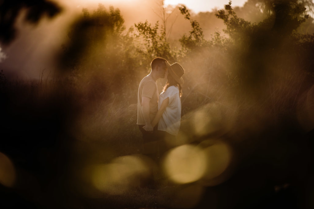 a couple hold hands and stand nose to nose during their engagement session