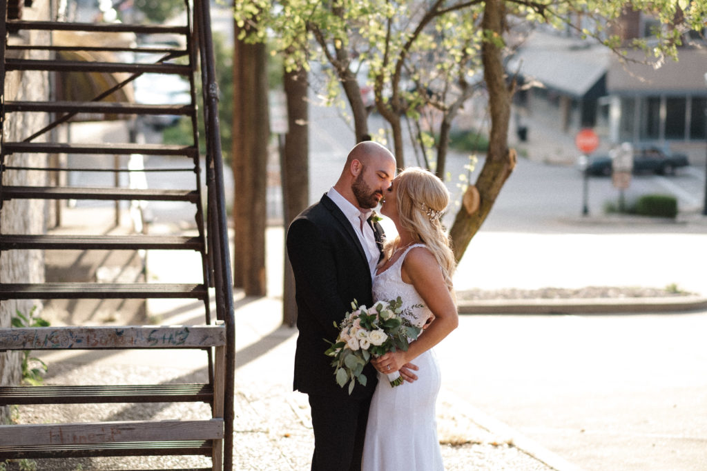 bride and groom kissing in a street during their golden hour downtown wedding photos