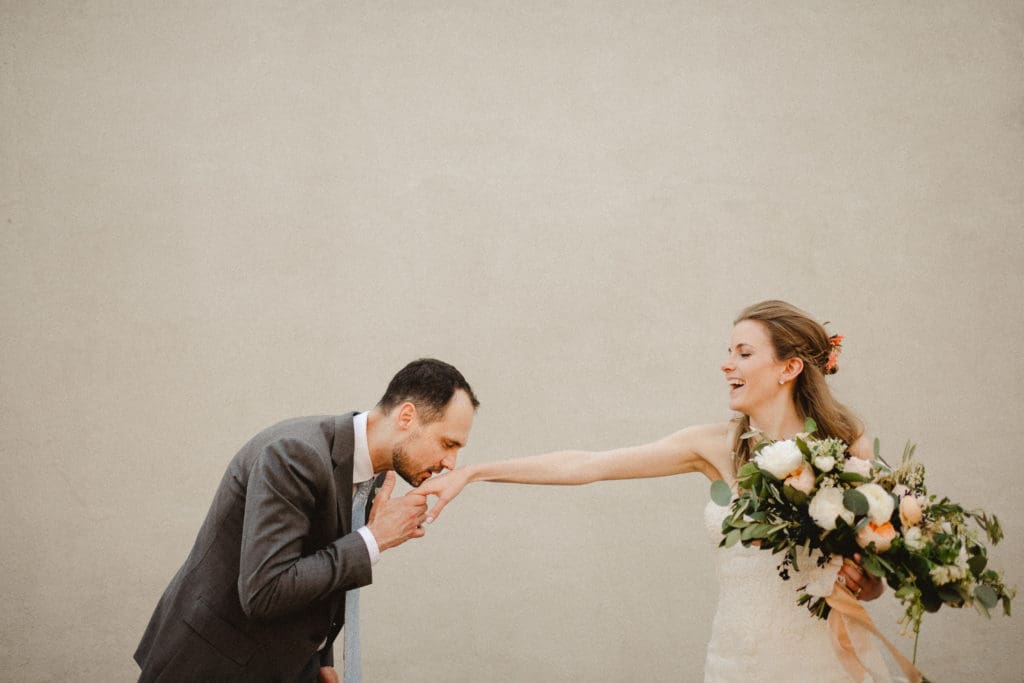 candid image of the groom kissing the bride's hand. the bride is laughing.