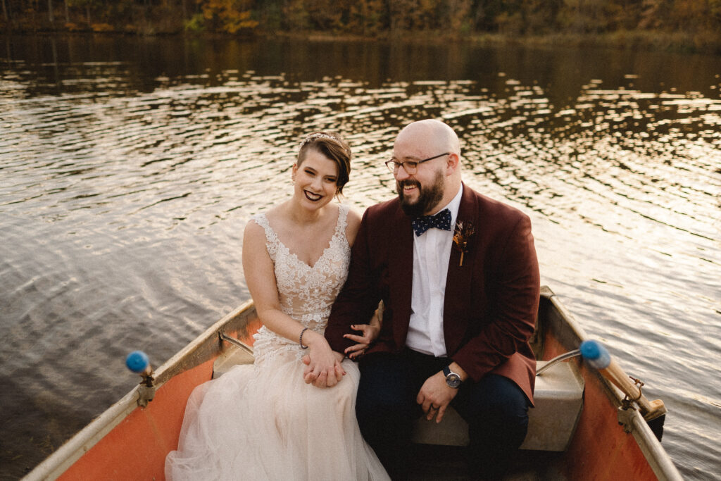 a couple snuggles together in an orange canoe on a lake in the rolling hills of the Ozarks just after their Missouri elopement