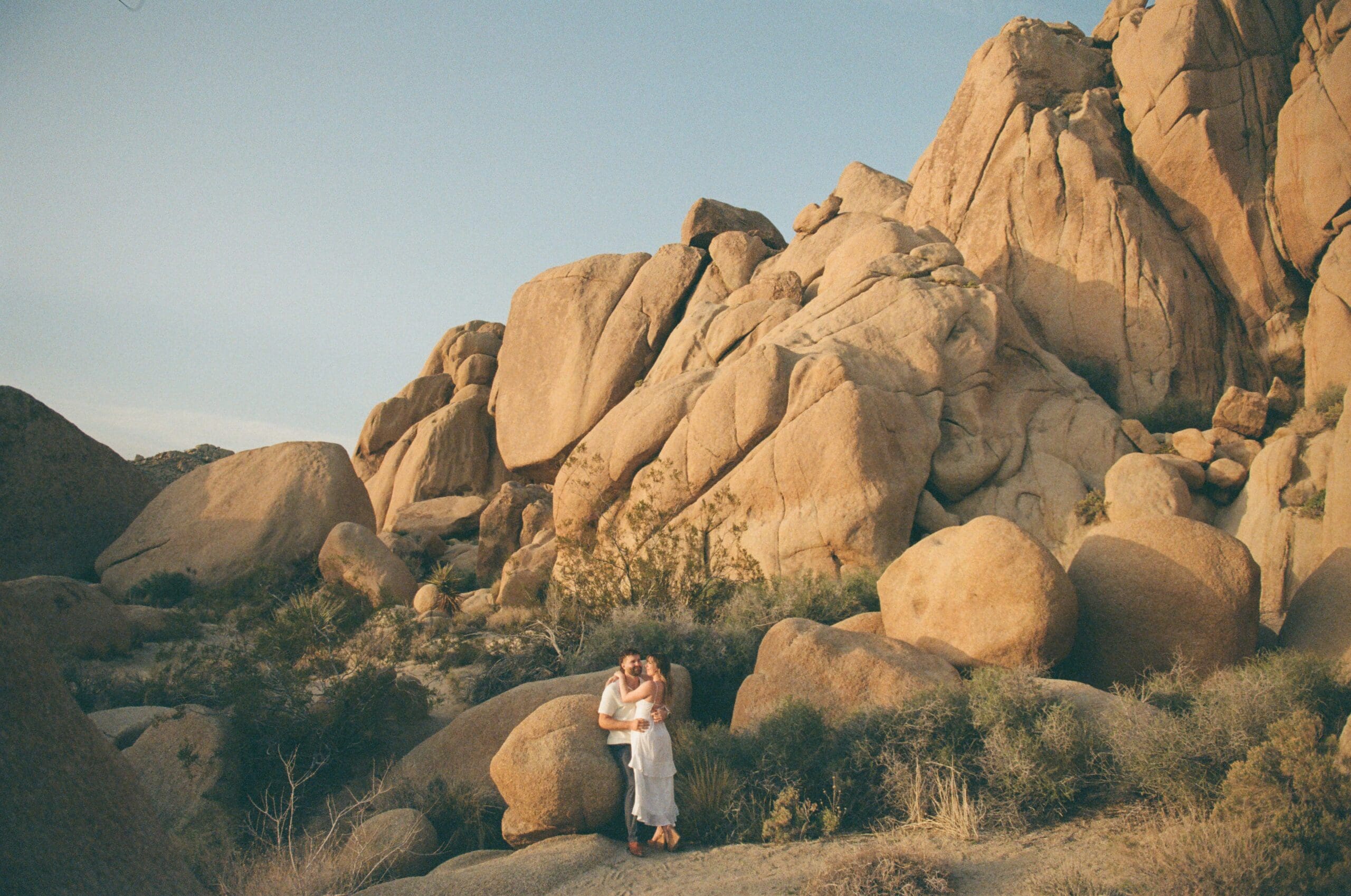 Documentaryl-style image of a couple eloping by giant rocks in Joshua Tree National Park taken on 35mm film.